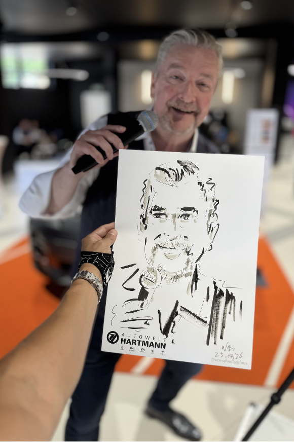 Mann mit Mikrofon hinter seinem fertigen Porträt auf Zeichenpapier mit Autowelt-Hartmann-Logo