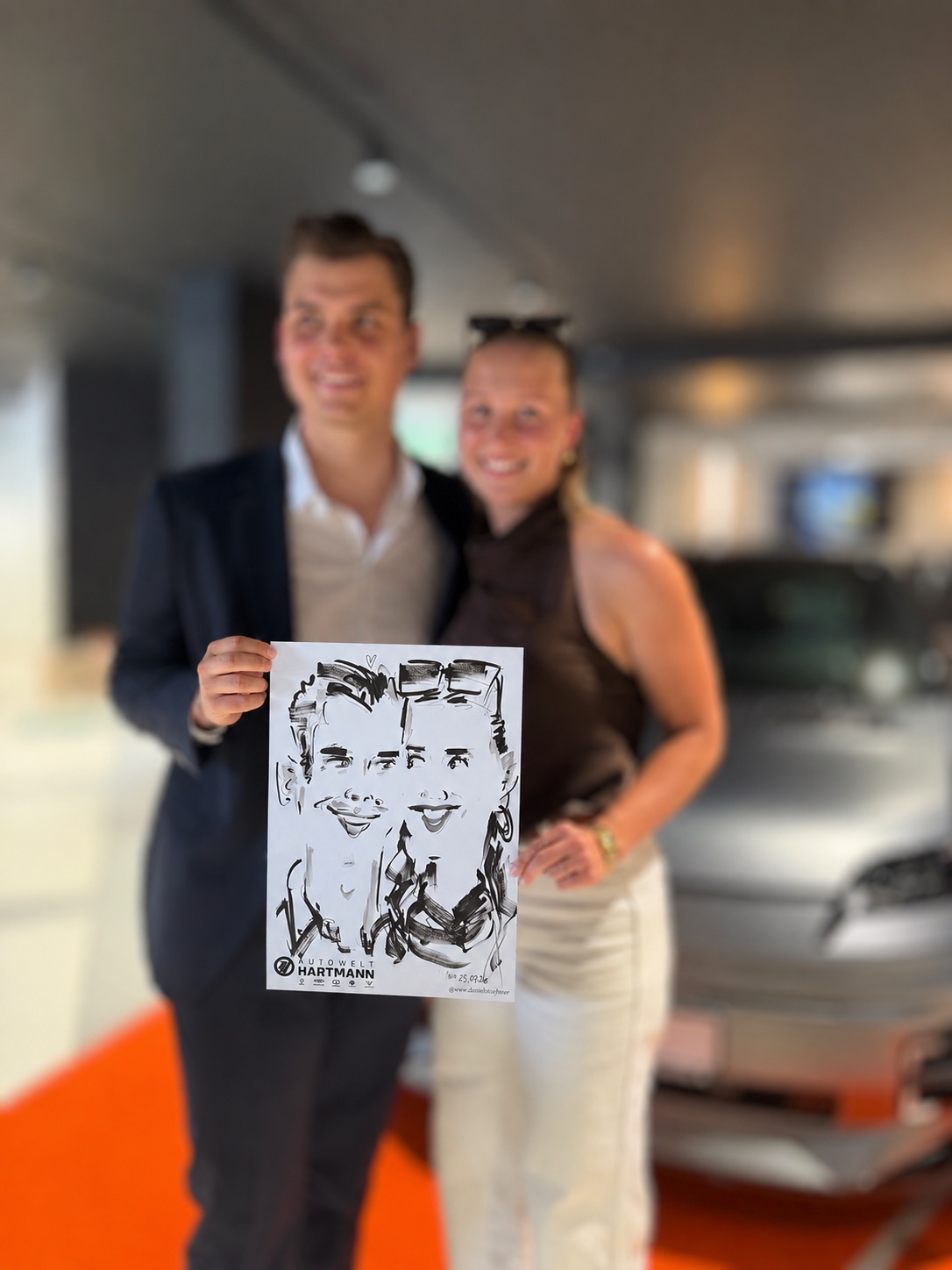 Junges Paar präsentiert seine live gezeichnete Karikatur bei Autowelt Hartmann