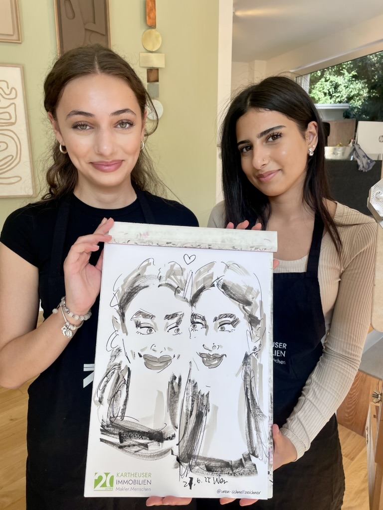 Zwei Frauen präsentieren gemeinsam ihre live gezeichnete Karikatur