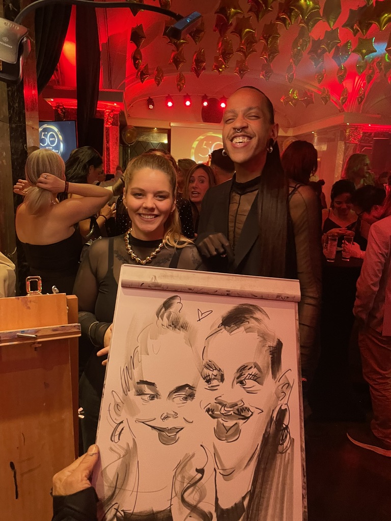 Zwei Gäste präsentieren ihre live gezeichnete Karikatur bei einer Veranstaltung